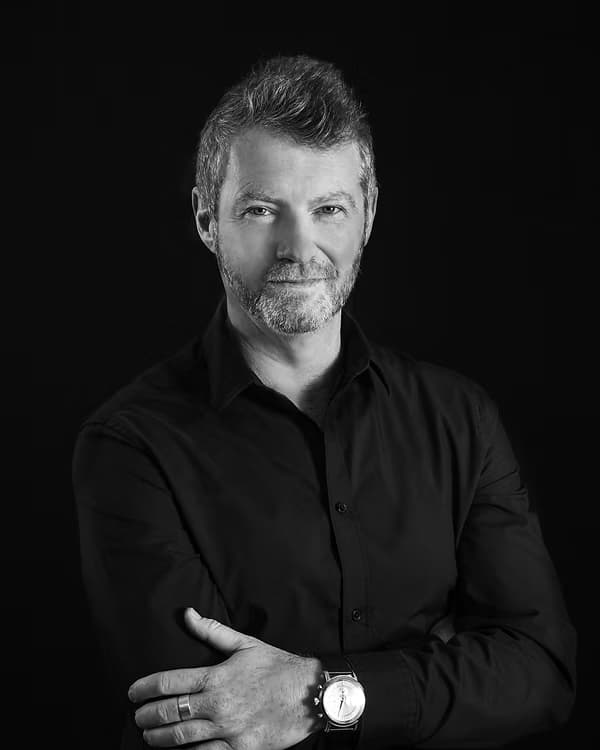 Craig Ralston, armen over elkaar, in een zwart-wit studioportret